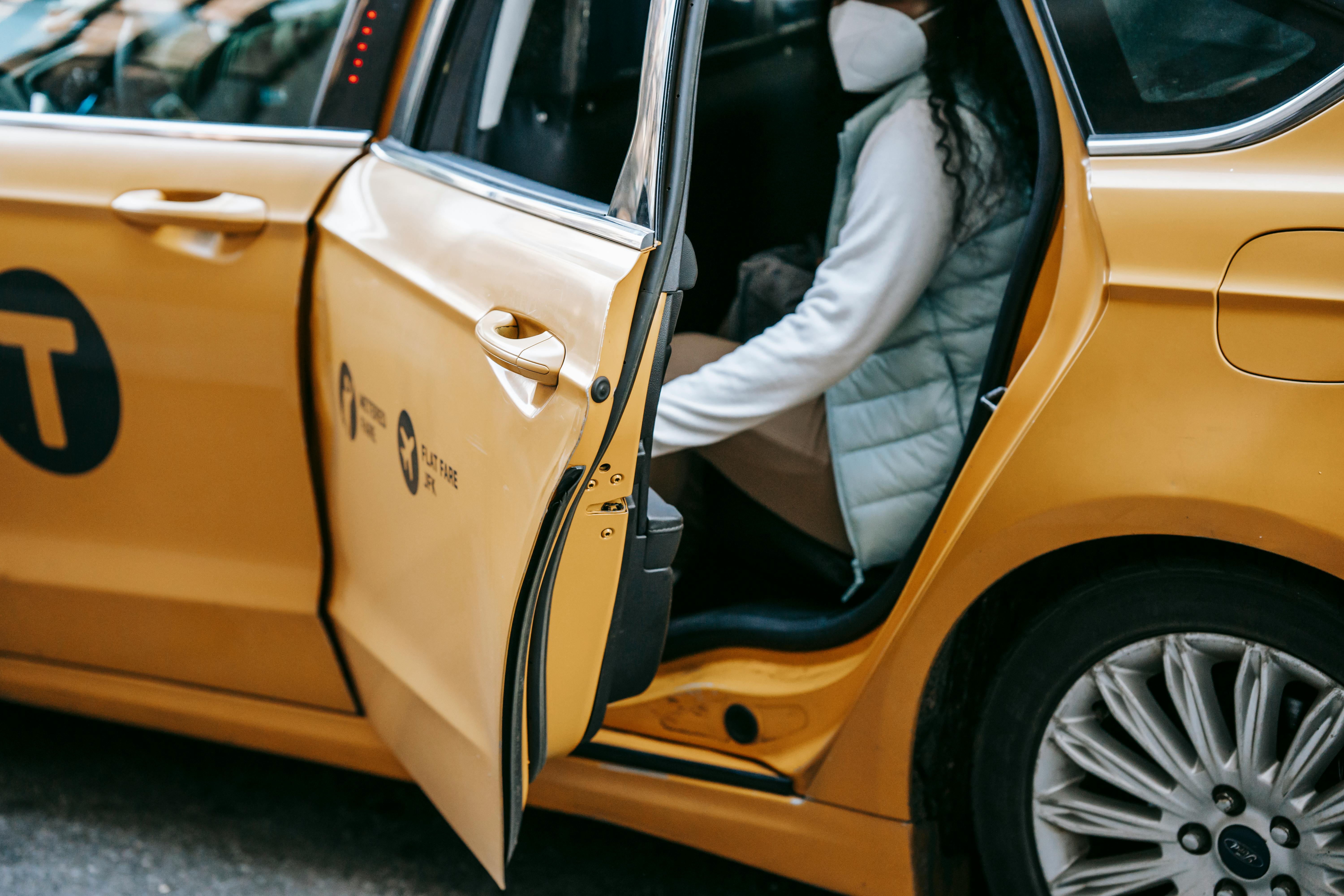 A person wearing a mask entering a taxi