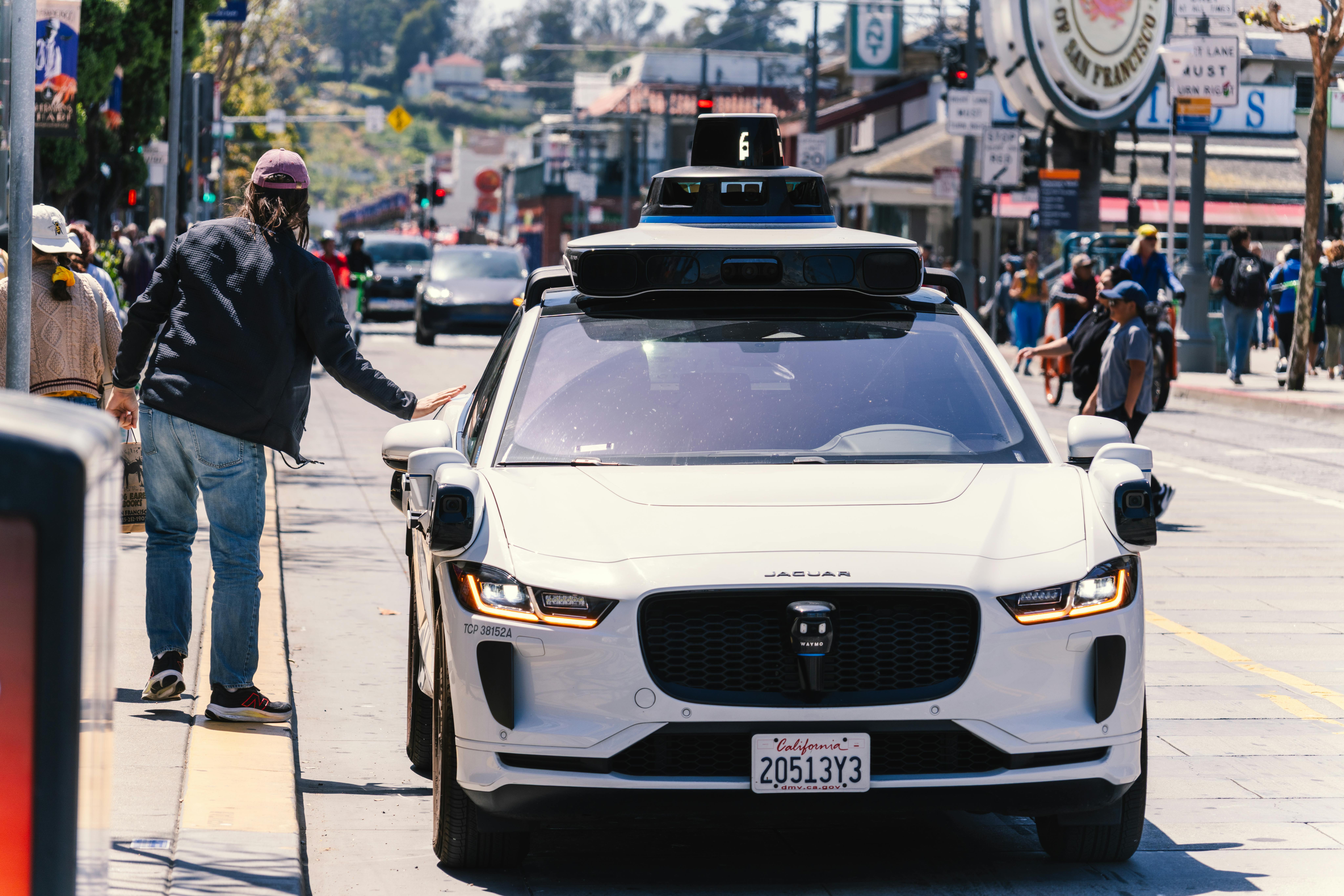 A customer opening the door of a Waymo